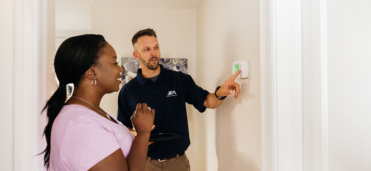 JEA Employee Helping Customer with AC Thermostat